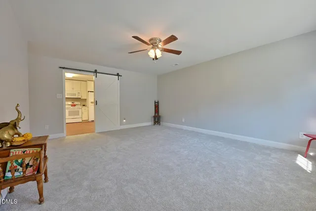 a view of an empty room with window and a kitchen