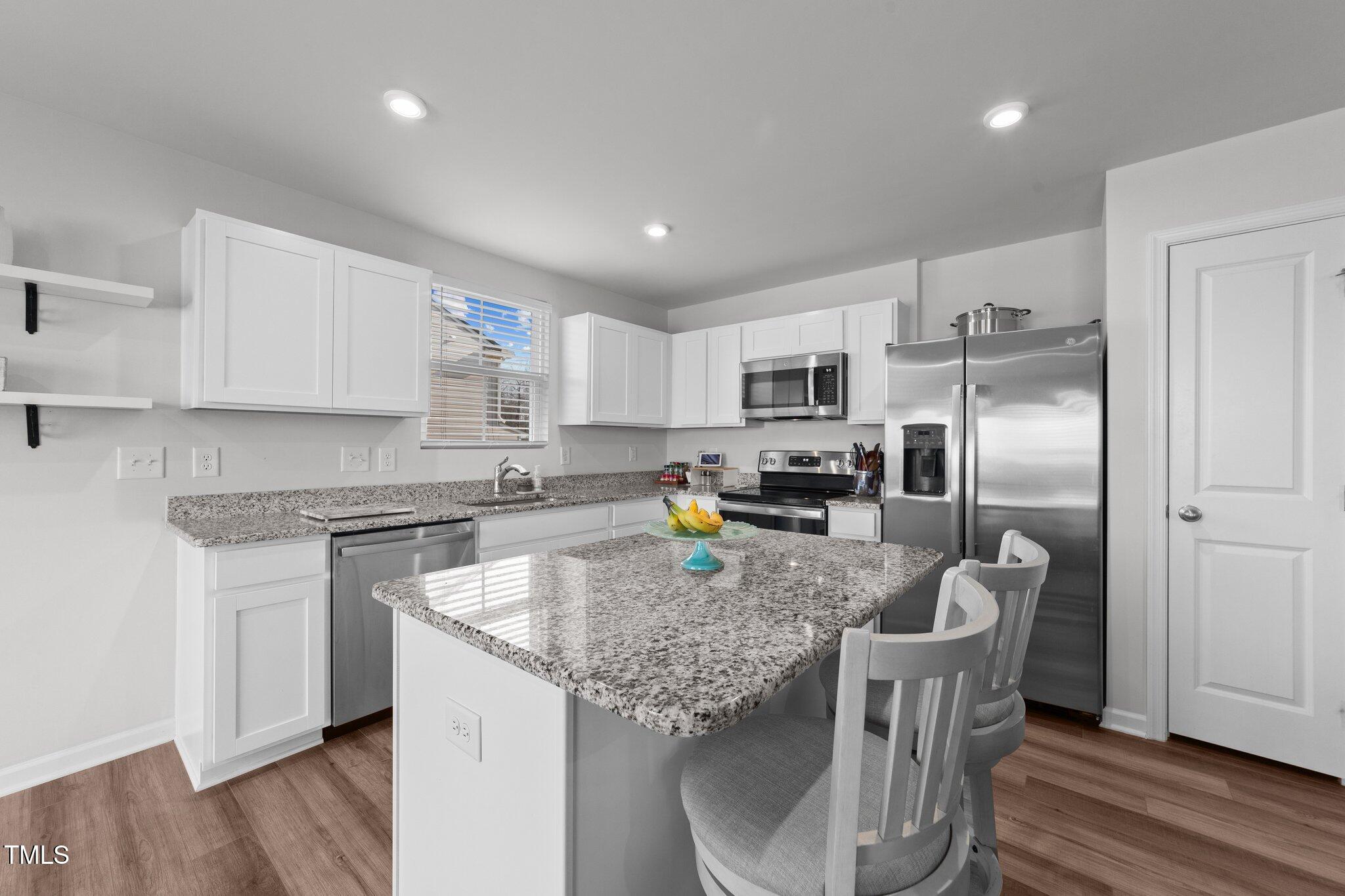 45 Florentine Court Angier, NC 27501 - Photo 20 of 27 a kitchen with stainless steel appliances granite countertop a stove top oven a refrigerator a sink and dishwasher with wooden floor