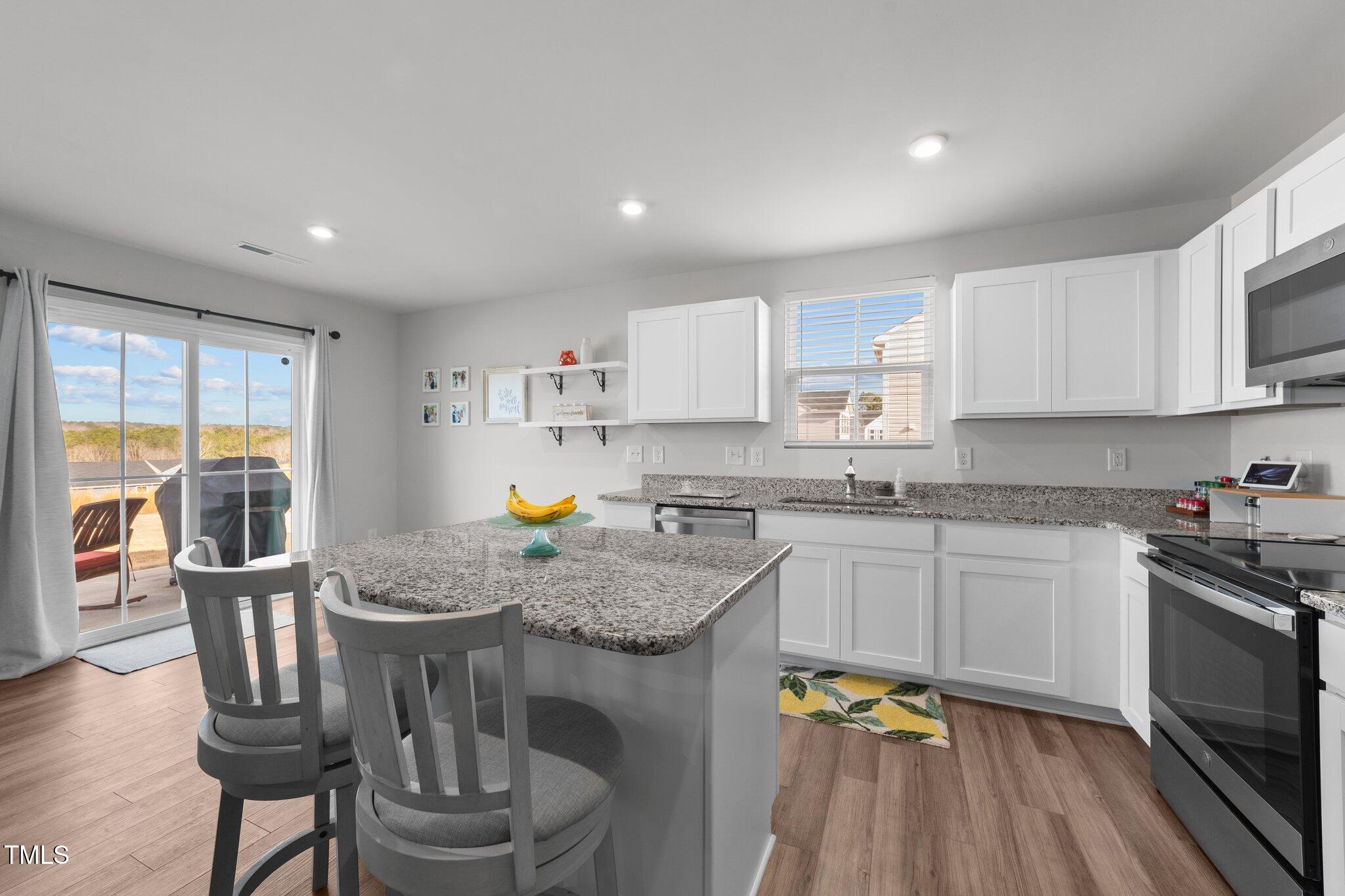 45 Florentine Court Angier, NC 27501 - Photo 22 of 27 a kitchen with stainless steel appliances granite countertop a stove a sink a microwave a dining table and chairs with wooden floor