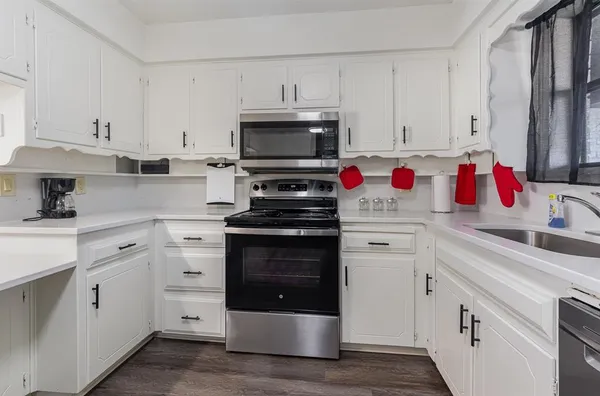 a kitchen with white cabinets and appliances