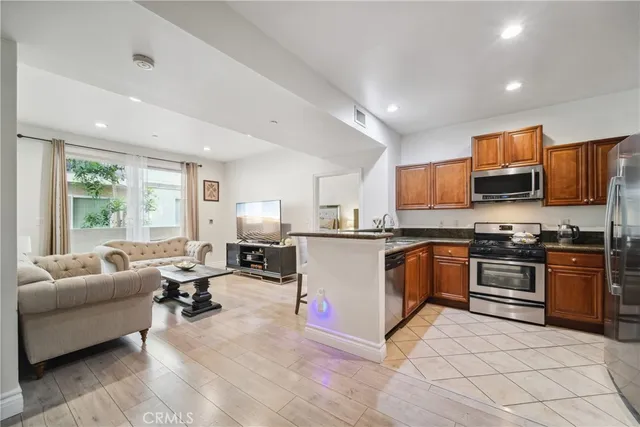 a large white kitchen with stainless steel appliances granite countertop a stove and a living room