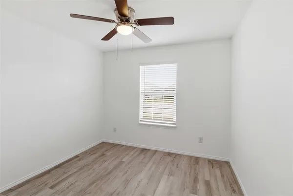 an empty room with a window and a fan