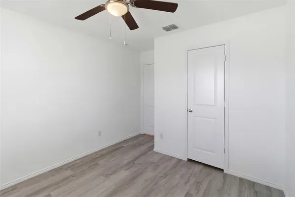 an empty room with wooden floor ceiling fan and window