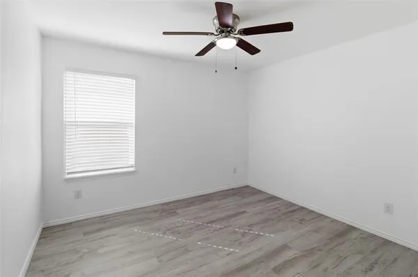 an empty room with a window and a fan