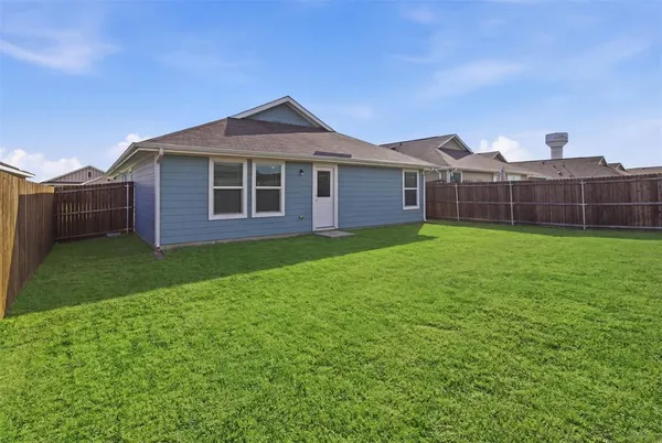 a view of a yard in front of a house with plants and large tree