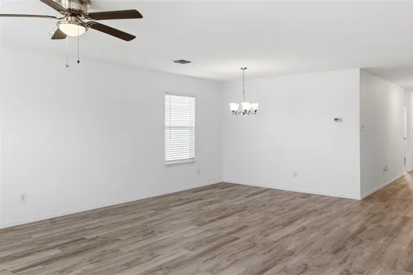 an empty room with wooden floor fan and windows