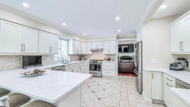 a kitchen with stainless steel appliances kitchen island granite countertop a stove refrigerator and cabinets