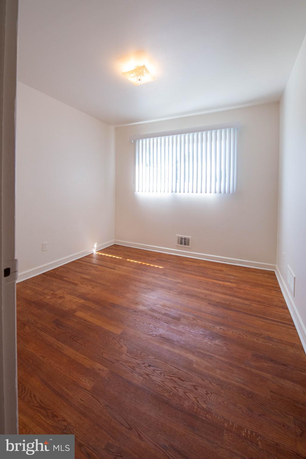 7408 Shirley Road Baltimore, MD 21207 - Photo 9 of 25 an empty room with wooden floor and windows