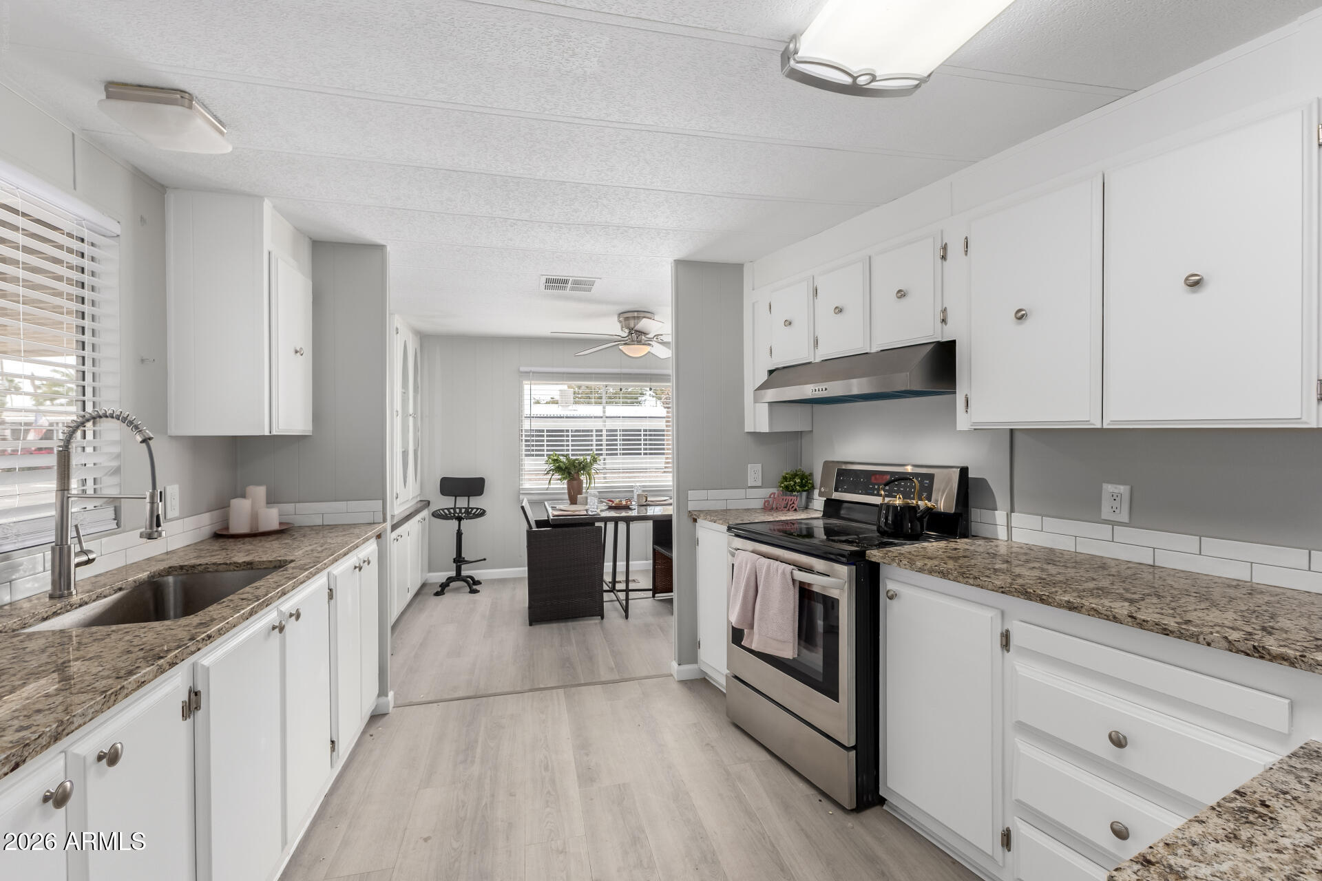 3104 East Broadway Road, Unit 30 Mesa, AZ 85204 - Photo 11 of 28 a kitchen with granite countertop white cabinets sink and stainless steel appliances