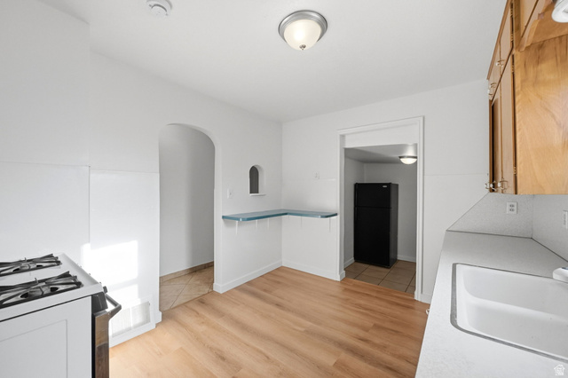 708 9th Street Ogden, UT 84404 - Photo 12 of 17 Kitchen with freestanding refrigerator, arched walkways, light wood-type flooring, white gas range, and light countertops