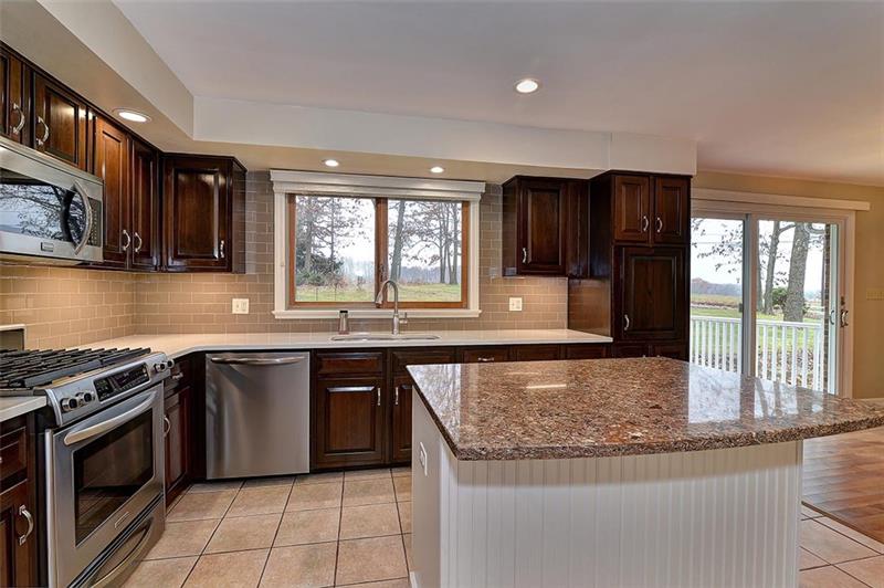 163 Glen Rape Road Rochester, PA 15074 - Photo 7 of 25 Kitchen 2016 remodel enjoys ceramic floor, Quartz, Island w/ breakfast bar, upscale spacious cabinetry, SS, & sink window and slider door overlooking/accessing the majesty yard.