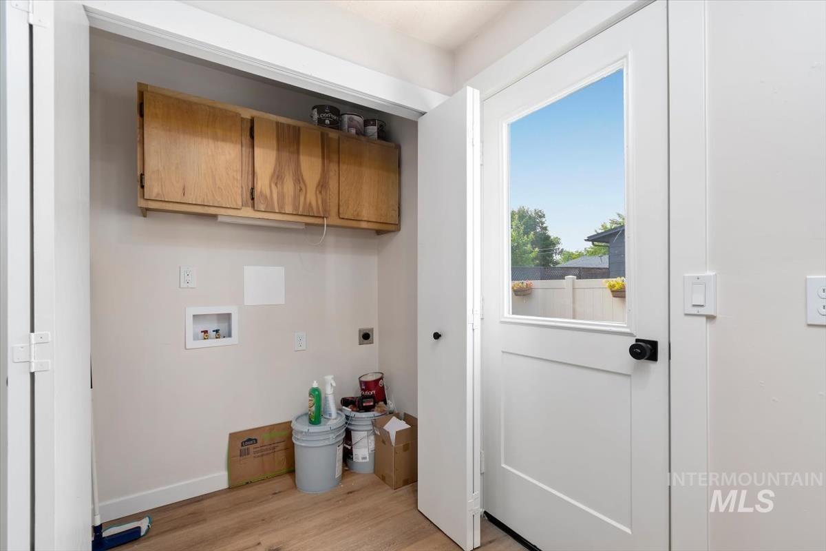 3005 West Hester Street Boise, ID 83702 - Photo 20 of 32 Dedicated utility space featuring wood-finish flooring, a white paneled door with an integrated window, and upper cabinetry for storage