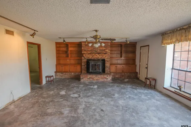an empty room with fireplace and windows