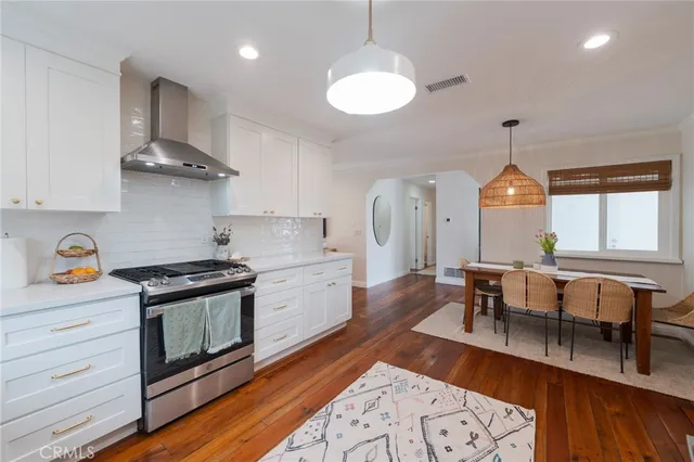 a kitchen with stainless steel appliances granite countertop a stove a sink a dining table and chairs with wooden floor