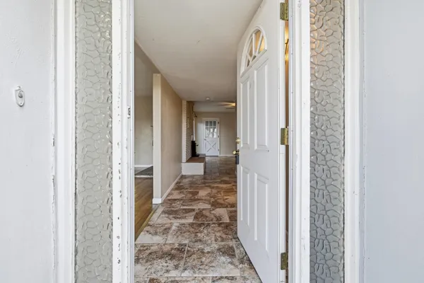 a view of a hallway with wooden floor and a bathroom
