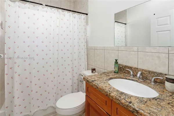 a bathroom with a granite countertop toilet sink and mirror