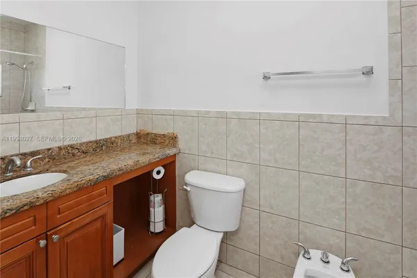 a bathroom with a granite countertop toilet and a sink
