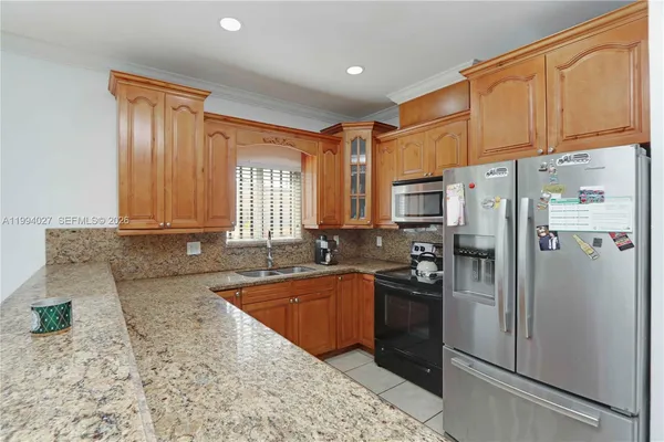 a kitchen with granite countertop a refrigerator a sink a stove and cabinets