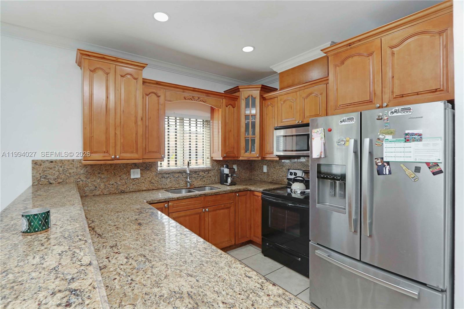 12245 Southwest 218th Street Miami, FL 33170 - Photo 7 of 32 a kitchen with granite countertop a refrigerator a sink a stove and cabinets