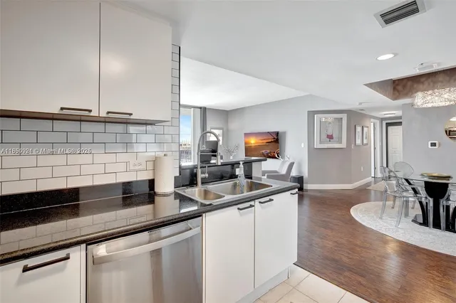 a kitchen with stainless steel appliances a sink a stove and white cabinets