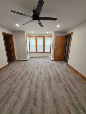 a view of empty room with wooden floor and fan