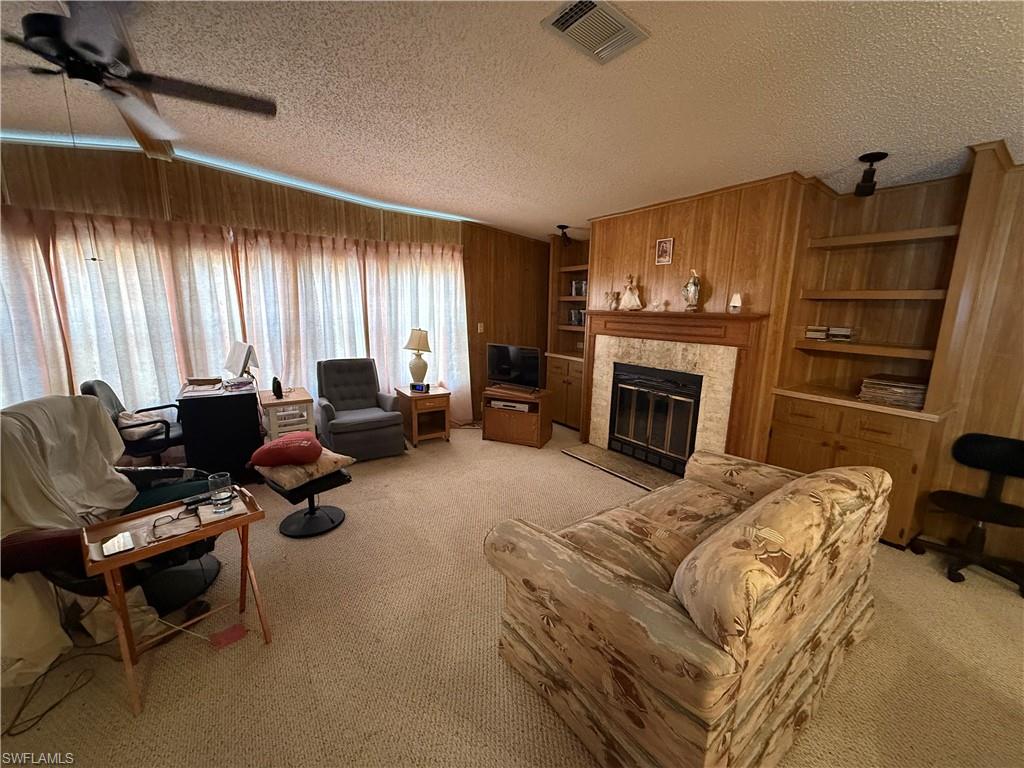 76 Atlantic Way, Unit 76 Naples, FL 34104 - Photo 17 of 18 Living room with built in features, a tiled fireplace, light carpet, a textured ceiling, and ceiling fan