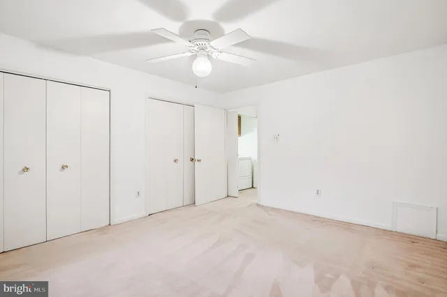 an empty room with a fan & a window