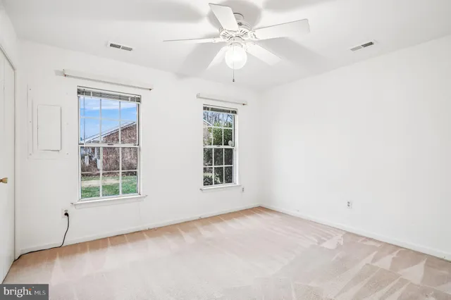 an empty room with windows and ceiling fan