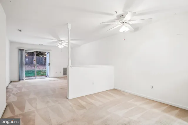en empty room with windows and ceiling fan
