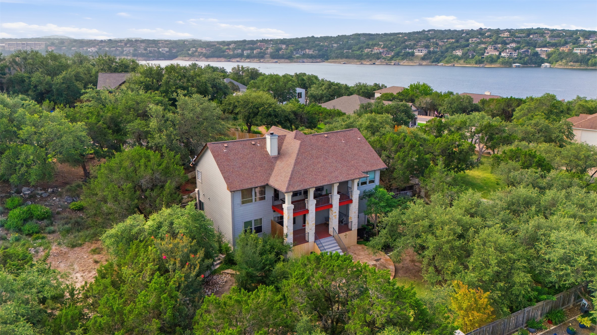 700 Augusta Circle Point Venture, TX 78645 - Photo 26 of 35 Hillside home with multiple levels of outdoor living space, nestled among mature trees, offering water views.