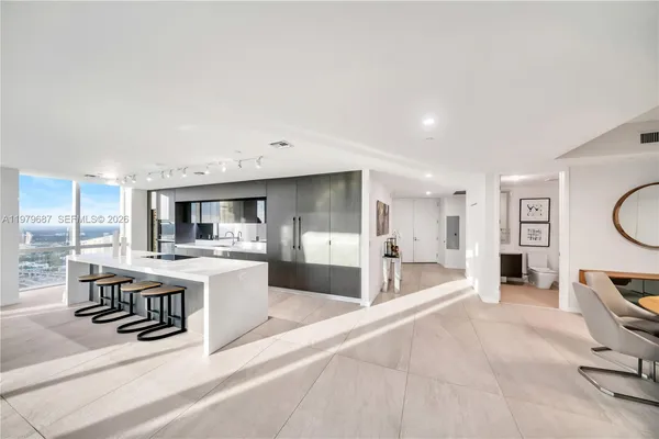 a large white kitchen with a large window and stainless steel appliances