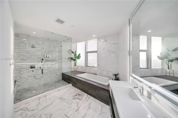 a spacious bathroom with a double vanity sink a large mirror and shower