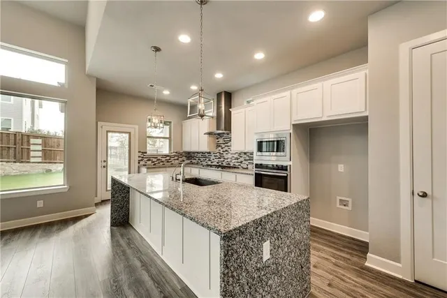 a large kitchen with kitchen island a large counter top and stainless steel appliances
