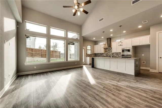 a view of an empty room with kitchen view and a window