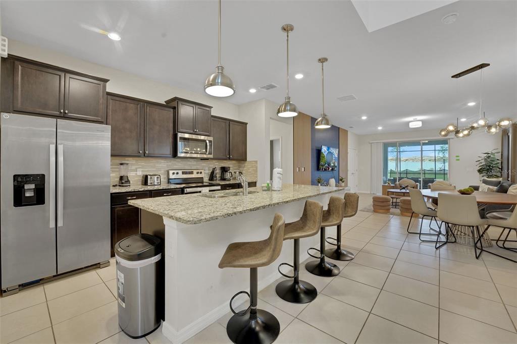 4450 Kaipo Road Davenport, FL 33897 - Photo 11 of 66 a kitchen with stainless steel appliances granite countertop a sink a stove a refrigerator and chairs
