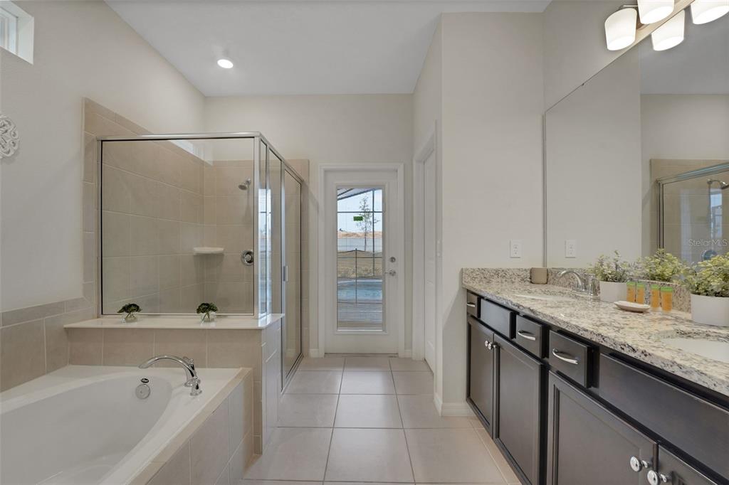 4450 Kaipo Road Davenport, FL 33897 - Photo 15 of 66 a bathroom with a granite countertop sink mirror and a bathtub