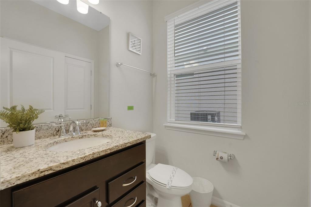 4450 Kaipo Road Davenport, FL 33897 - Photo 16 of 66 a bathroom with a granite countertop sink a toilet and mirror