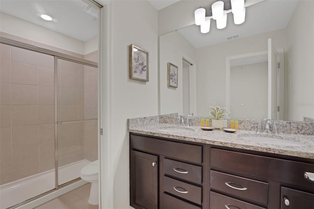 4450 Kaipo Road Davenport, FL 33897 - Photo 27 of 66 a bathroom with a granite countertop sink a mirror and a shower