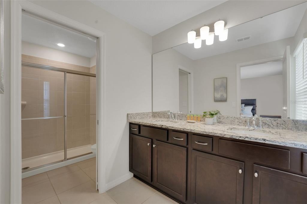 4450 Kaipo Road Davenport, FL 33897 - Photo 30 of 66 a bathroom with a granite countertop sink a mirror and a shower
