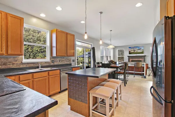 a large kitchen with kitchen island a large window and chairs