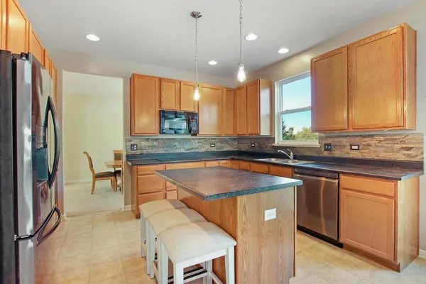 a kitchen with stainless steel appliances granite countertop a sink a stove a refrigerator and island