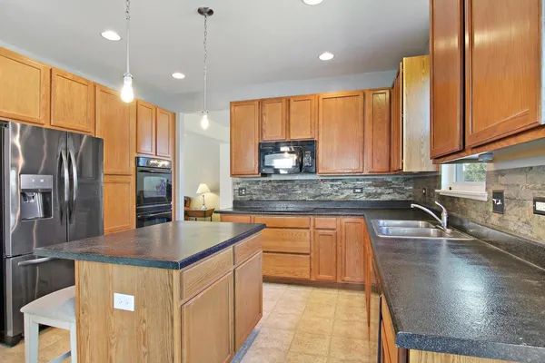 a kitchen with stainless steel appliances granite countertop a sink a stove and a refrigerator