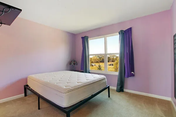 a bed sitting in a bedroom next to a window