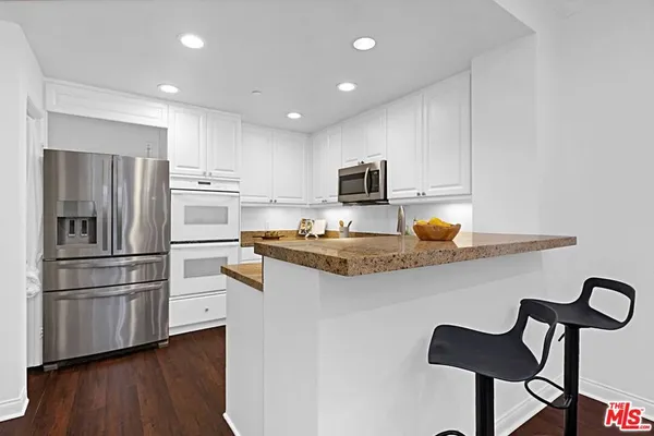a kitchen with kitchen island white cabinets and stainless steel appliances