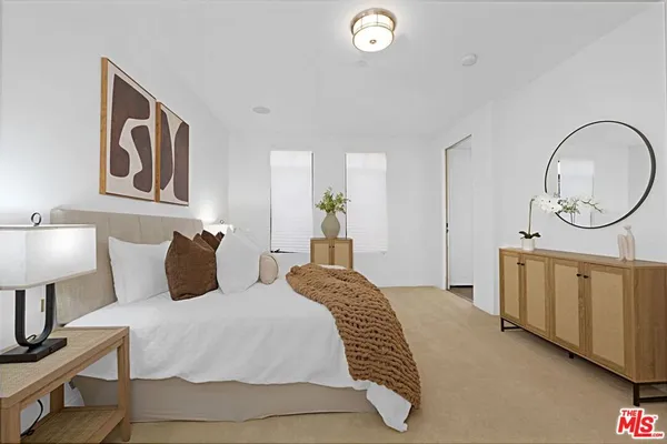 a bedroom with a bed a mirror on dresser and a chandelier