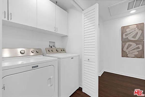 a view of washer and dryer with wooden cabinets