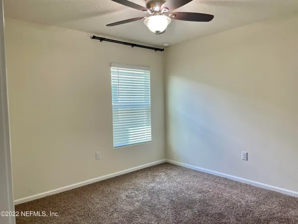 an empty room with a window and a fan