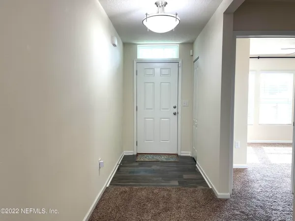 a view of a hallway with wooden floor and chandelier