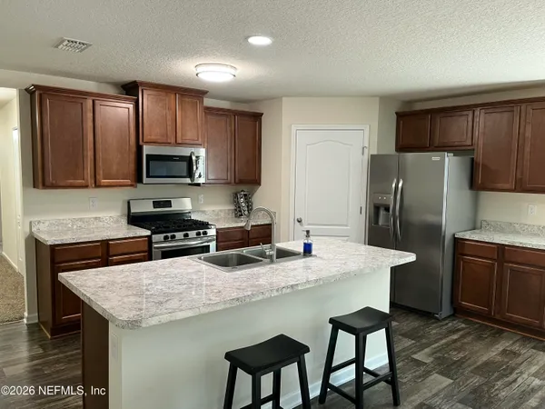 a kitchen with stainless steel appliances granite countertop a refrigerator a stove a sink a dining table and chairs