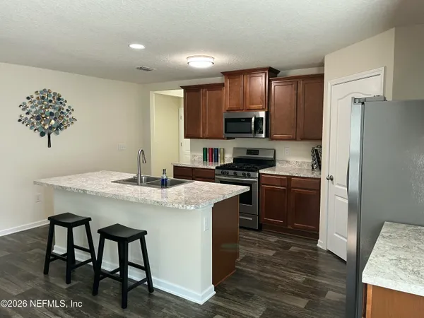 a kitchen with a refrigerator a stove a sink and a dining table with wooden floor